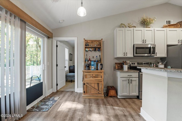 kitchen with white cabinetry, vaulted ceiling, hanging light fixtures, stainless steel appliances, and light hardwood / wood-style floors