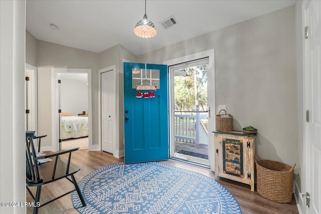 foyer featuring wood-type flooring and vaulted ceiling