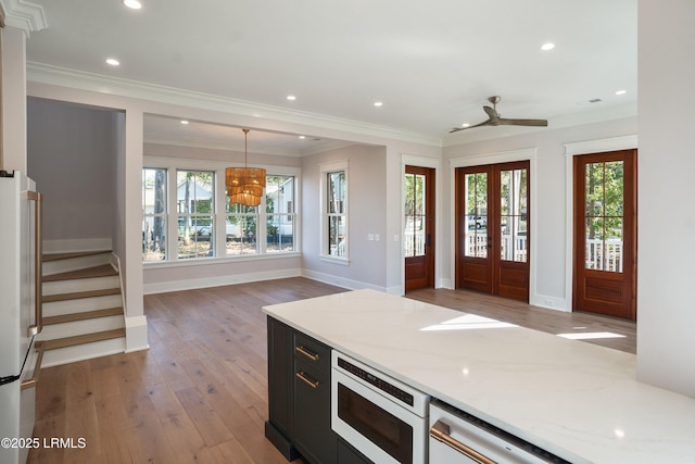 kitchen featuring built in microwave, hanging light fixtures, high end refrigerator, and light stone counters