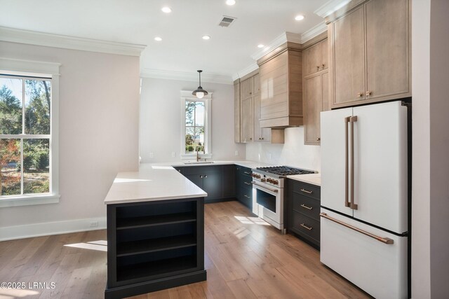 kitchen featuring sink, white appliances, light hardwood / wood-style flooring, hanging light fixtures, and light brown cabinets