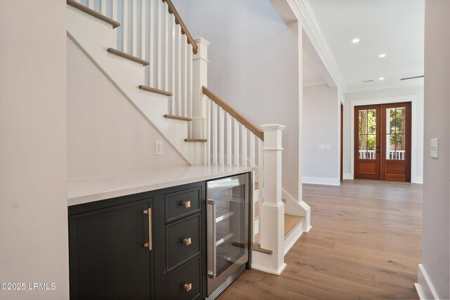 foyer featuring french doors, ornamental molding, beverage cooler, and light hardwood / wood-style floors