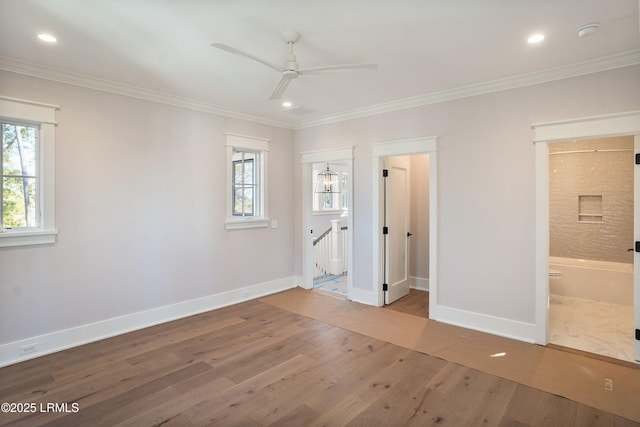 unfurnished bedroom featuring ceiling fan, ensuite bath, hardwood / wood-style floors, and multiple windows