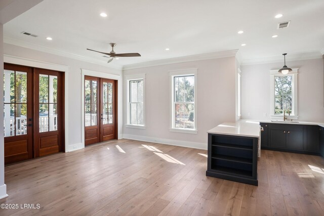 foyer featuring sink, crown molding, light hardwood / wood-style flooring, a healthy amount of sunlight, and french doors