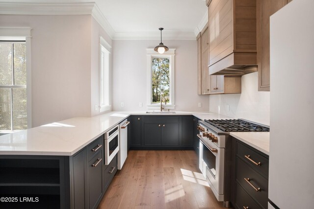 kitchen with sink, light wood-type flooring, kitchen peninsula, pendant lighting, and white appliances