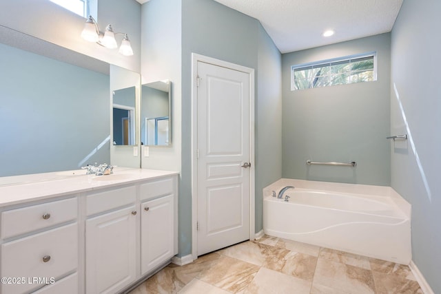 bathroom with vanity, a textured ceiling, and a bathtub