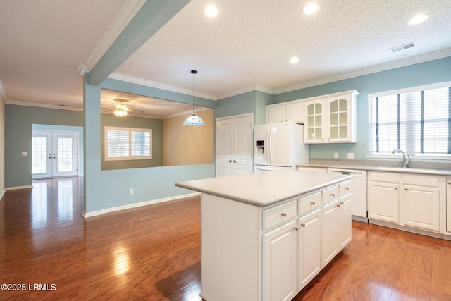 kitchen with a center island, pendant lighting, white appliances, a healthy amount of sunlight, and white cabinets