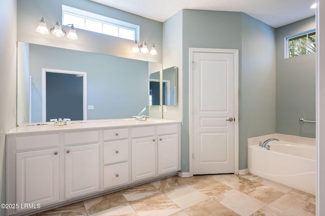 bathroom featuring vanity, a bath, and a textured ceiling