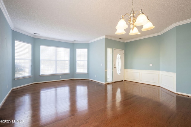 empty room with dark wood-type flooring, ornamental molding, and a chandelier