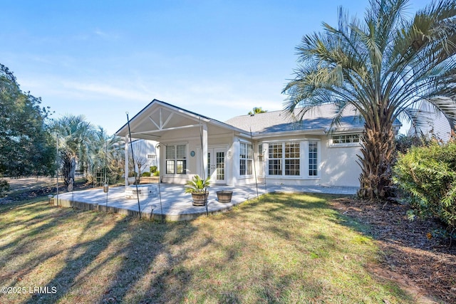 back of property with a yard and a patio