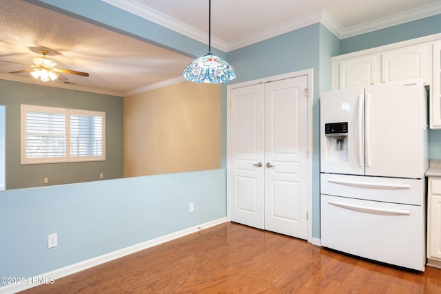 kitchen with white cabinetry, decorative light fixtures, white refrigerator with ice dispenser, and ornamental molding