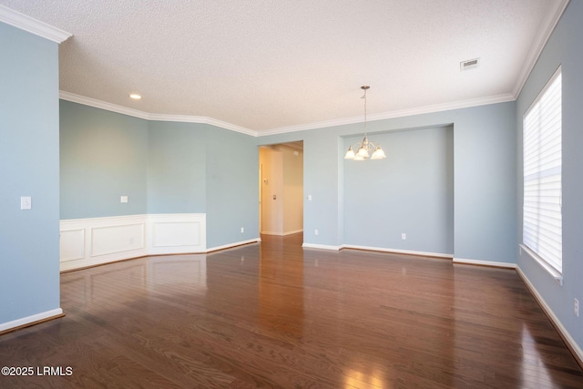 spare room with ornamental molding, dark hardwood / wood-style floors, a wealth of natural light, and an inviting chandelier