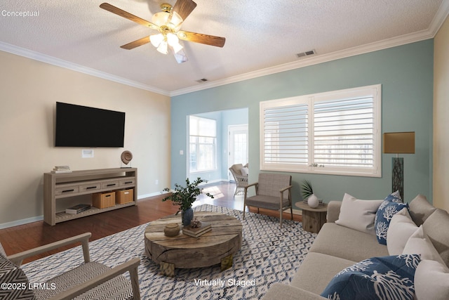 living room with dark wood-type flooring, ceiling fan, ornamental molding, and a textured ceiling