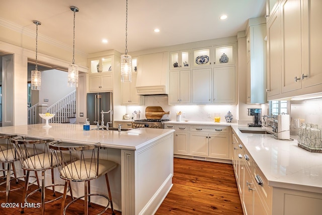 kitchen featuring sink, custom exhaust hood, dark hardwood / wood-style floors, light stone countertops, and a kitchen island with sink