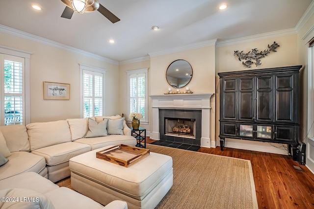 living room with ornamental molding, plenty of natural light, dark hardwood / wood-style flooring, and a tiled fireplace