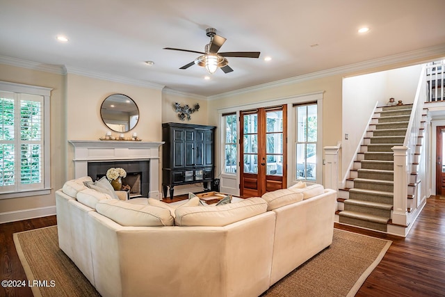 living room with dark wood-type flooring, french doors, crown molding, ceiling fan, and a tiled fireplace