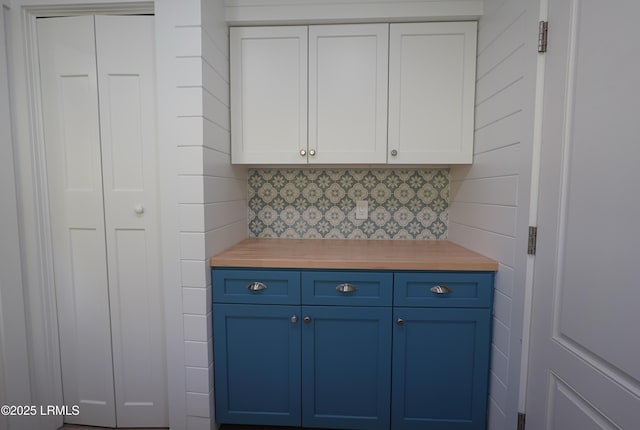 kitchen featuring white cabinets, backsplash, and blue cabinetry