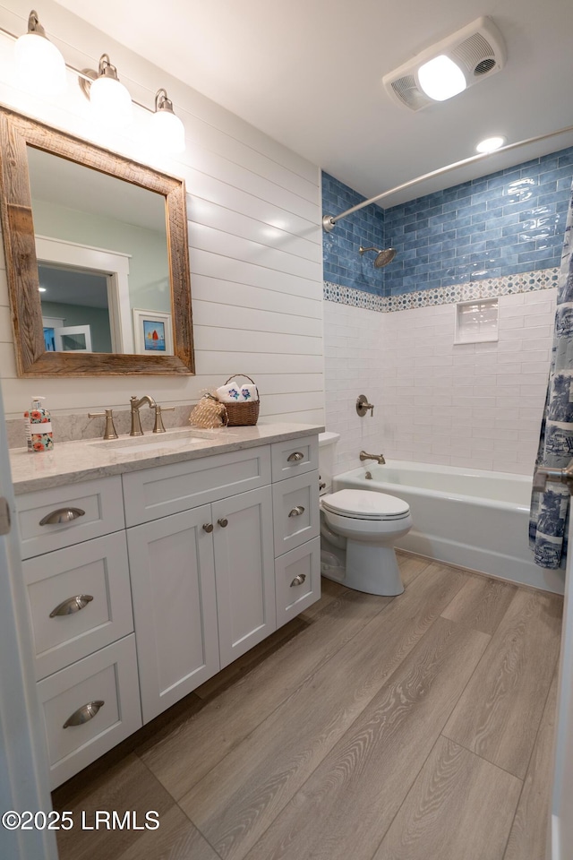 bathroom with vanity, wood finished floors, toilet, and shower / bathtub combination with curtain