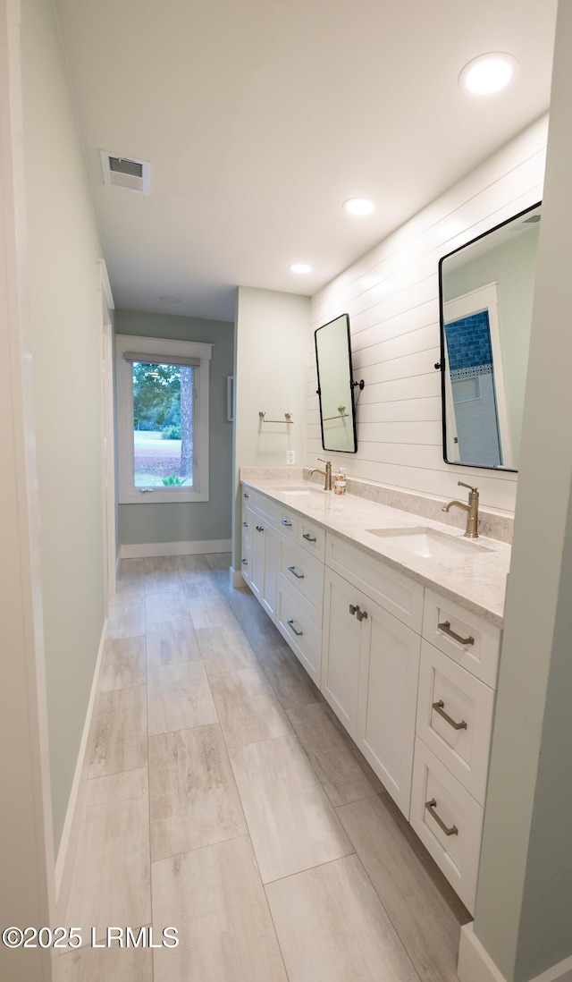 bathroom with double vanity, baseboards, visible vents, and a sink