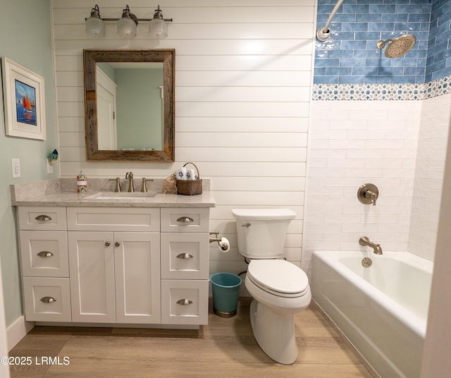 bathroom featuring bathtub / shower combination, vanity, toilet, and wood finished floors