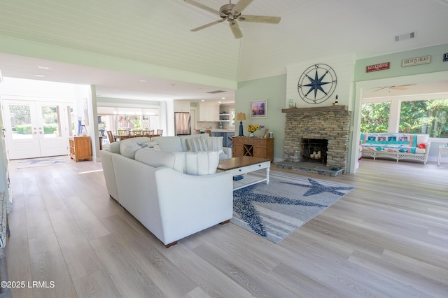 living room featuring light wood-type flooring, visible vents, plenty of natural light, and a high ceiling