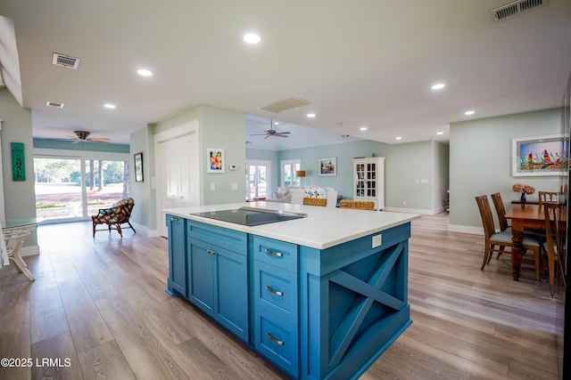 kitchen featuring visible vents, open floor plan, blue cabinets, black electric cooktop, and light countertops