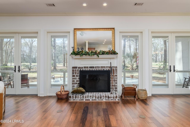 living room featuring crown molding, hardwood / wood-style floors, a fireplace, and french doors