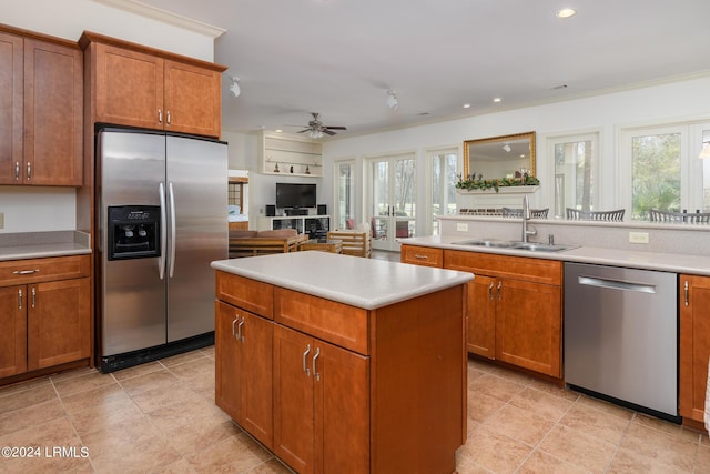 kitchen with sink, crown molding, ceiling fan, appliances with stainless steel finishes, and a kitchen island