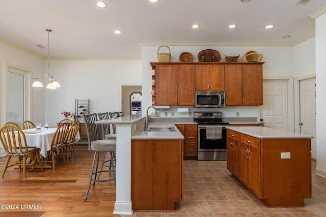 kitchen featuring sink, crown molding, stainless steel appliances, decorative light fixtures, and kitchen peninsula