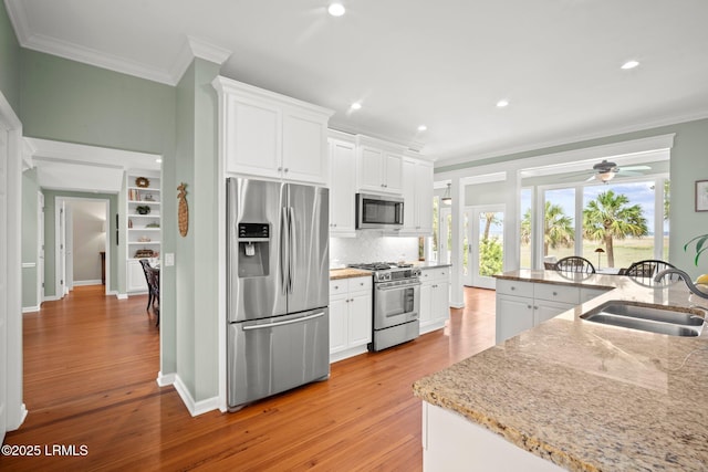 208 Cotton Dike Rd, Saint Helena Island, SC 29920 - kitchen featuring stainless steel appliances, ornamental molding, a sink, light wood-type flooring, and backsplash