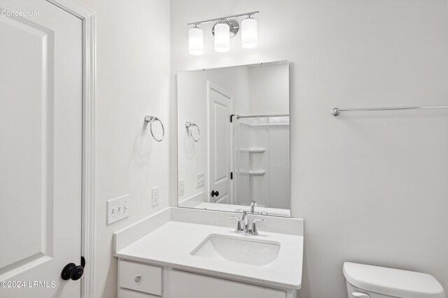 bathroom with walk in shower, vanity, and toilet