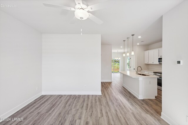 kitchen with a sink, baseboards, light countertops, appliances with stainless steel finishes, and light wood finished floors