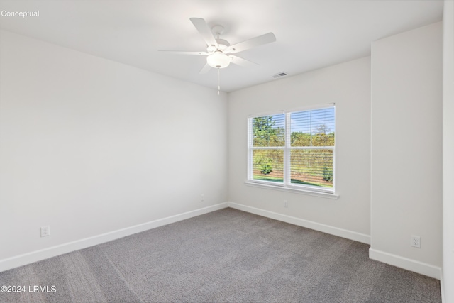 carpeted spare room with baseboards, visible vents, and a ceiling fan