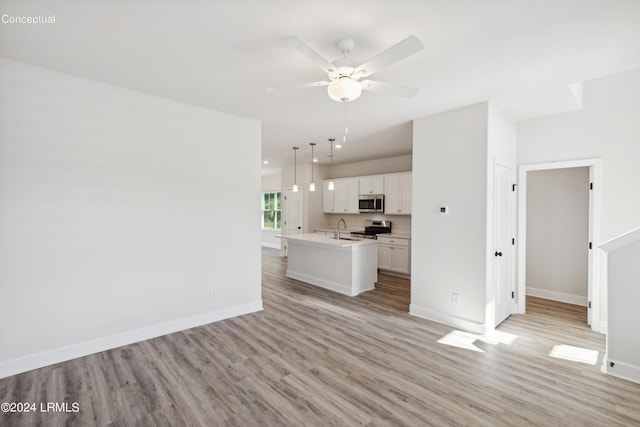 unfurnished living room with light wood-style flooring, baseboards, and a sink