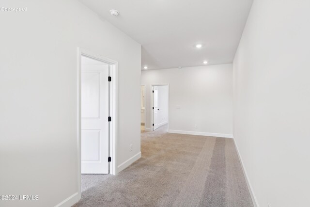 hall with recessed lighting, baseboards, and light colored carpet