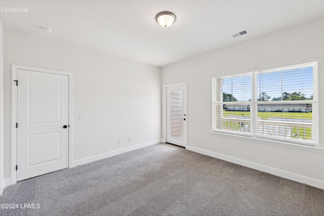 carpeted spare room featuring visible vents and baseboards