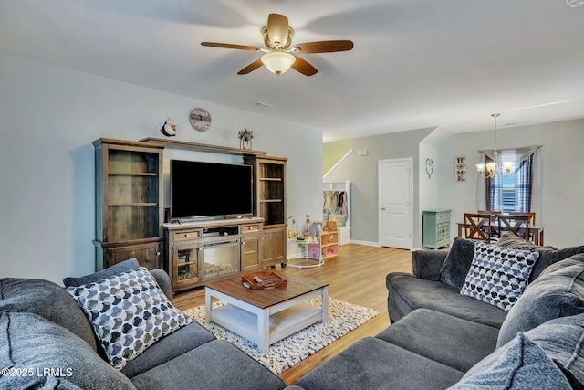 living room with ceiling fan with notable chandelier and light wood-type flooring