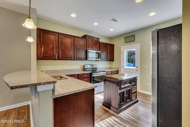 kitchen with pendant lighting, sink, a kitchen bar, kitchen peninsula, and stainless steel appliances