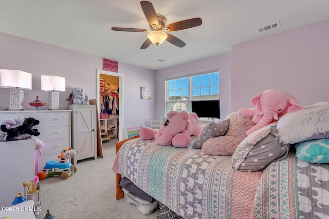 bedroom with ceiling fan, a walk in closet, light carpet, and a closet