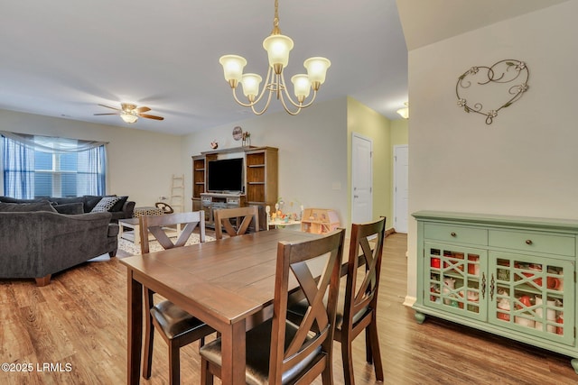 dining space with ceiling fan with notable chandelier and wood-type flooring