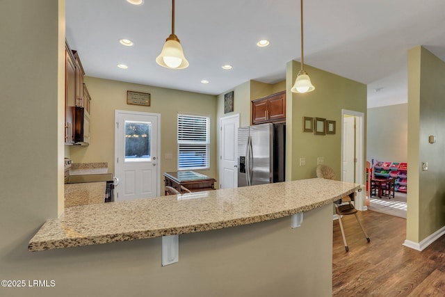 kitchen featuring range with electric cooktop, kitchen peninsula, a breakfast bar area, and stainless steel refrigerator with ice dispenser