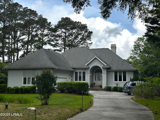 ranch-style house with a front lawn, a chimney, aphalt driveway, roof with shingles, and an attached garage