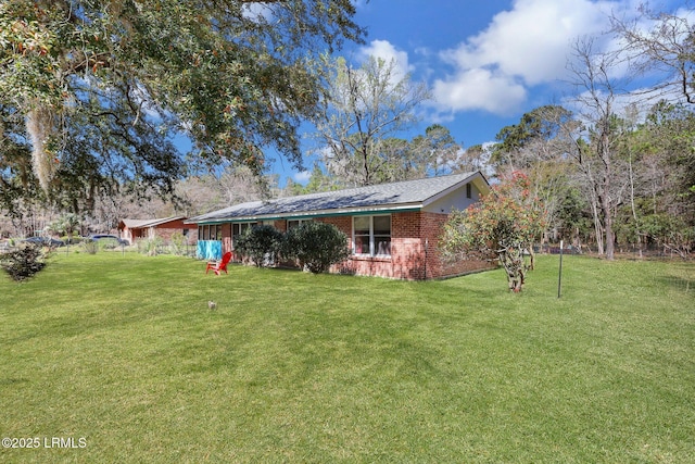 rear view of property featuring a yard and brick siding