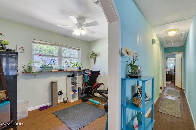 workout area with baseboards, attic access, a ceiling fan, and wood finished floors