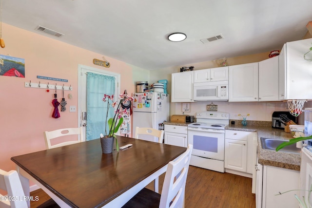 kitchen with dark wood finished floors, visible vents, white appliances, and white cabinetry