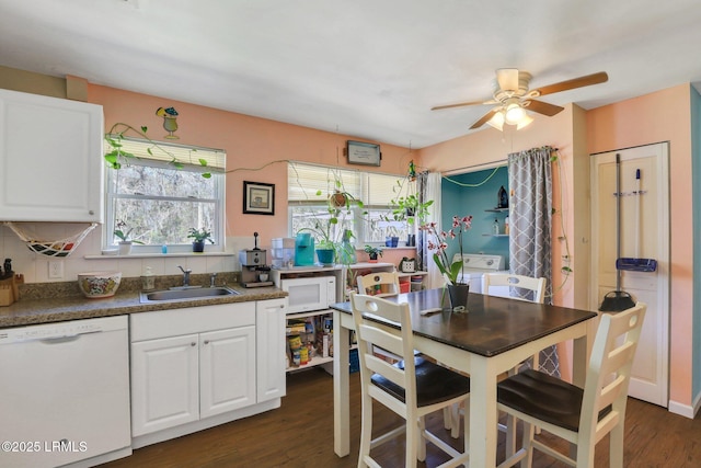 kitchen featuring a ceiling fan, washer and clothes dryer, a sink, white appliances, and white cabinets