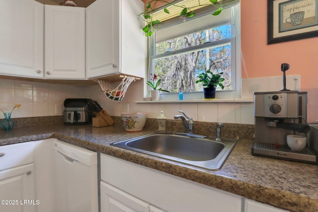 kitchen featuring tasteful backsplash, a sink, white cabinetry, and white dishwasher