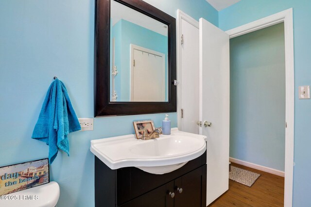 bathroom with baseboards, toilet, wood finished floors, and vanity