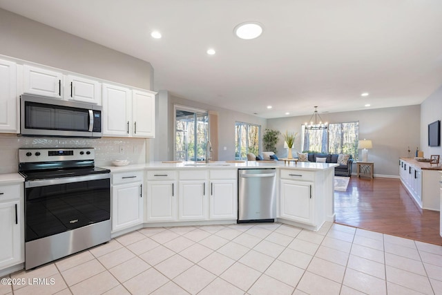 kitchen featuring sink, white cabinetry, light tile patterned floors, kitchen peninsula, and stainless steel appliances