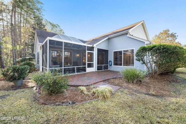 back of property featuring a sunroom, a lawn, and a patio area