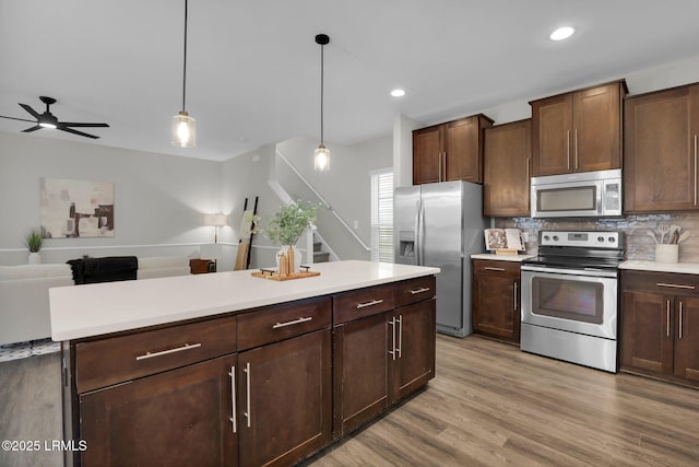 kitchen with tasteful backsplash, decorative light fixtures, dark brown cabinetry, and appliances with stainless steel finishes